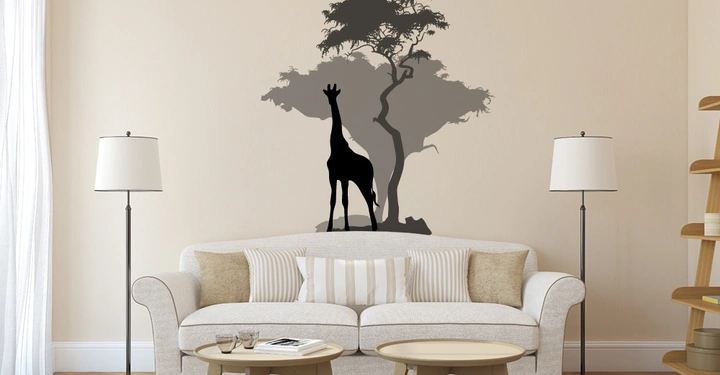 Wandsticker einer Giraffe und eines Baums schmückt eine beige Wohnzimmerwand neben einem weißen Sofa mit Kissen zwei Stehlampen runden Couchtischen ein Bücherregal und einem großen Fenster mit Vorhängen