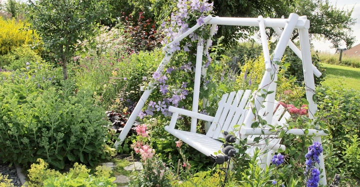 Die klassische Hollywoodschaukel aus Metall bringt eine romantsiche Nostalgie in den Garten.