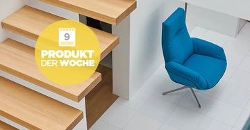 Blauer Stuhl steht auf weiß gefliestem Boden neben schwebenden Holztreppenstufen in einem modernen Raum Text PRODUKT DER WOCHE und Kalender mit Nummer 9 in gelbem Kreis