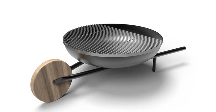 Runder schwarzer Grill mit Holzrad auf einer Seite stehend in einem weißen, leeren Raum.