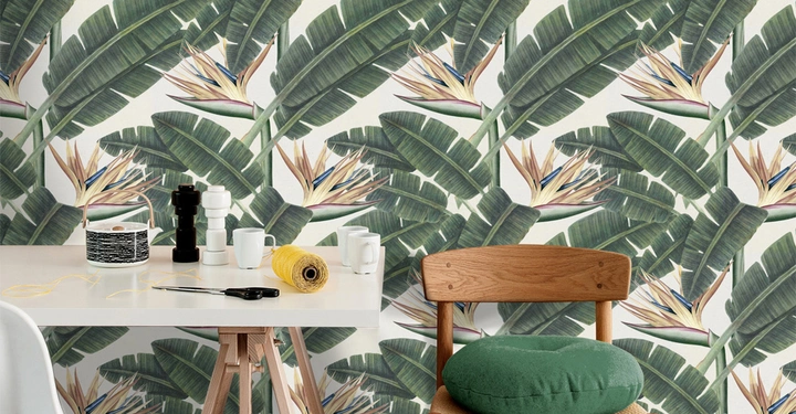 Galerie-Bild 4: Holzstuhl mit grünem Kissen steht am weißen Tisch auf dem Schere Garn Tassen und Salz und Pfefferstreuer liegen umgeben von Tapete mit Tropenmuster aus großen grünen Blättern und Exotischen Blüten