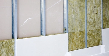 Wand mit Metallstreben zeigt Dämmstoff und Gipskartonplatten Teils unvollständig installiert in einer Baustellensituation