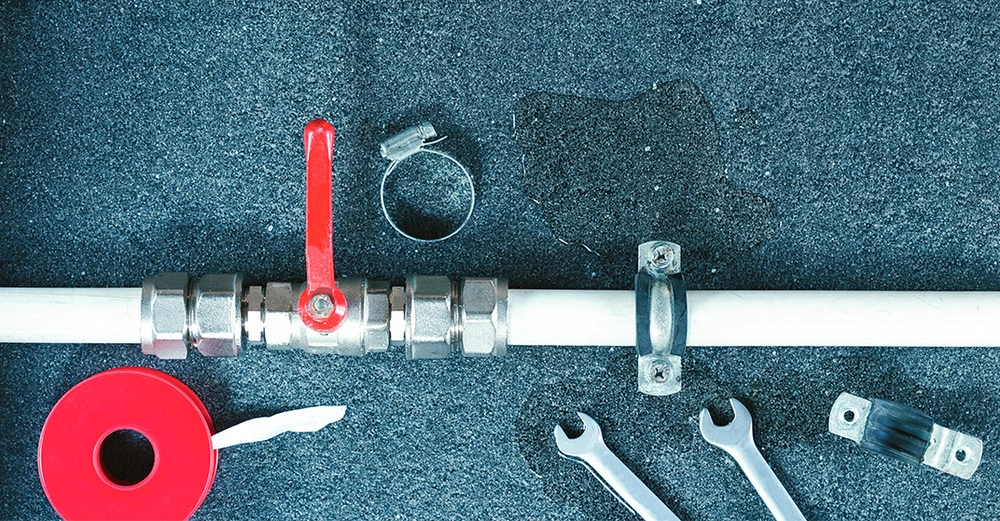 Klempnerwerkzeug und -ausrüstung liegt am Boden neben einem Rohr.