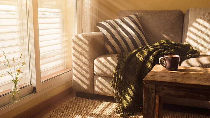 Wohnzimmer mit innenliegendem Sonnenschutz durch Jalousien, die Sonnenlicht filtern und für eine angenehme Atmosphäre sorgen.