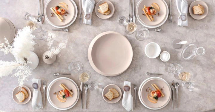 Draufsicht auf einen festlich gedeckten Tisch mit der Villeroy & Boch Kollektion NewMoon in Beige. Elegantes Gedeck für vier Personen mit minimalistischer Dekoration.