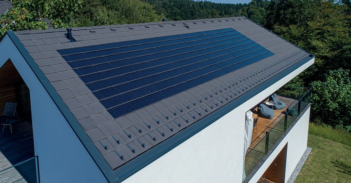 Solarmodule installieren Energie produzierend auf dem Dach eines modernen weißen Hauses umgeben von grünen Bäumen und Wiesen an einem sonnigen Tag