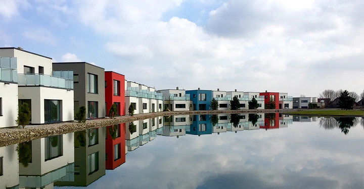 Galerie-Bild 1: Häuserreihe auf Schotter rund um See, bewölkter Himmel, bunte Fassaden
