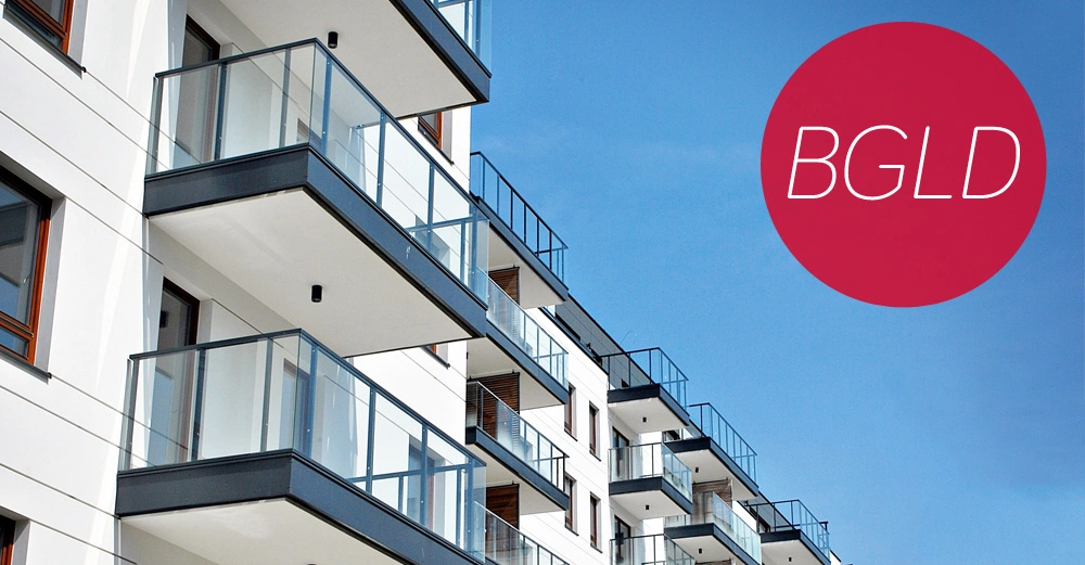 Mehrstöckiges Wohngebäude mit Glasbalkonen reihen sich entlang der Fassade blauer Himmel BGLD in rotem Kreis oben rechts