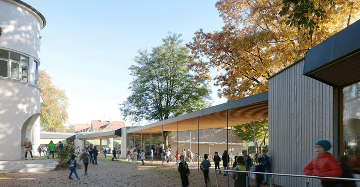 Galerie-Bild 8: Kinder spielen auf einem Schulhof zwischen modernen Gebäuden mit großen Fenstern unter herbstlichen Bäumen. Links rundes Gebäude, rechts rechteckiges Gebäude mit Holzverkleidung.