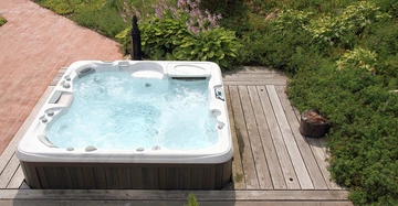 Ein eingebauter Whirlpool im Garten auf einer Holzterrasse. Überblick über moderne Whirlpool-Technik, Modelle und typische Kosten für Anschaffung und Betrieb zur privaten Nutzung.