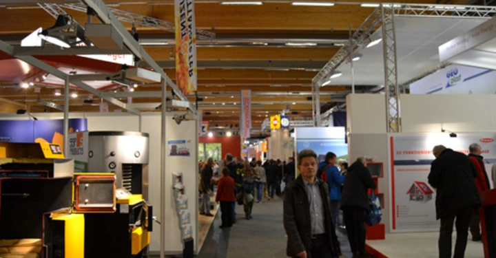 Galerie-Bild 13: Mann geht durch Passage in einer Messehalle umgeben von Ständen mit Ausstellungsstücken und Besuchern im Hintergrund.