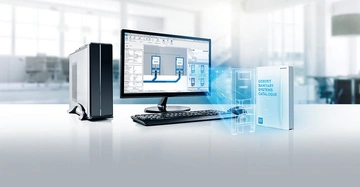 Ein Desktop-Computer zeigt Planungssoftware auf dem Bildschirm in einem hell beleuchteten Büro. Ein Katalog mit der Aufschrift GEBERIT SANITARY SYSTEMS CATALOGUE steht daneben.