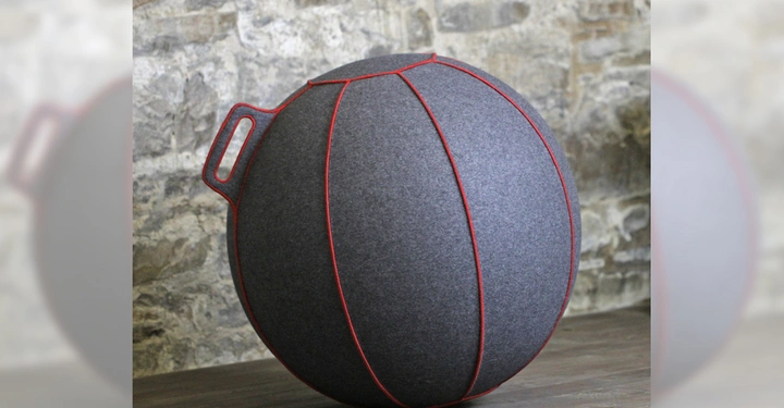 Galerie-Bild 4: Grauer Filzball mit roter Naht und Griff steht auf Holzboden vor steinerner Wand