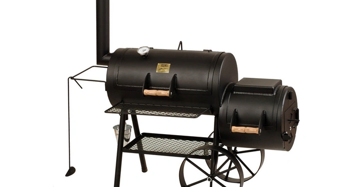 Galerie-Bild 6: Ein schwarzer Grillwagen mit Rädern hat zwei Holzkohlekammern und Holzgriff. Er steht auf einem Gitterrost in einem Innenraum. Text auf dem Grill lautet: **New Braunfels Bandera** and **New Braunfels, TX**