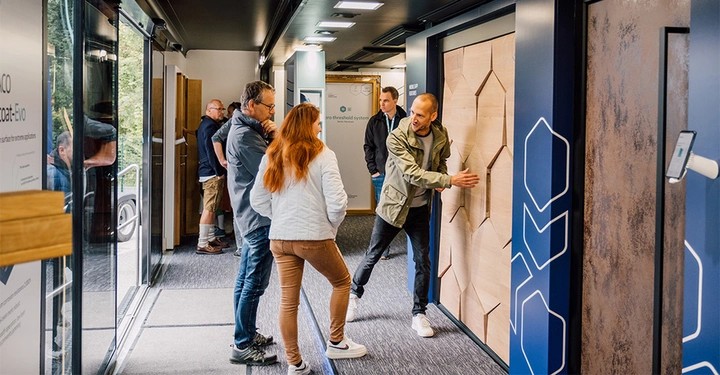 Mann zeigt Tür Inneneinrichtung Andere Menschen schauen interessiert zu