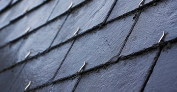 Dachschindeln werden von kleinen Metallhaken gehalten Die Schindeln sind in gleichmäßigen Reihen und leicht geneigt Das Umfeld ist unklar aber wahrscheinlich ein Dach eines Gebäudes