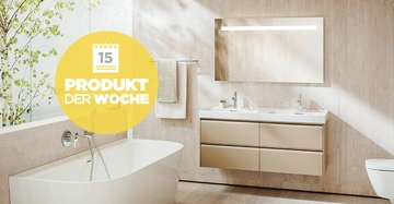 Freistehende Badewanne befindlich linke Seite daneben hängendes Handtuch vor einem beleuchteten Spiegel und Doppelwaschbecken in einem modern dekorierten Badezimmer Text: 15 PRODUKT DER WOCHE