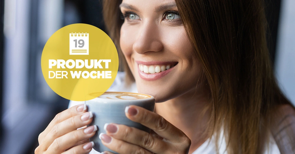 Eine Frau lächelt und hält eine Tasse mit Latte Art Kaffeetasse in beiden Händen in einem gut beleuchteten Innenraum Text auf einem gelben Kreis 19 Produkt der Woche