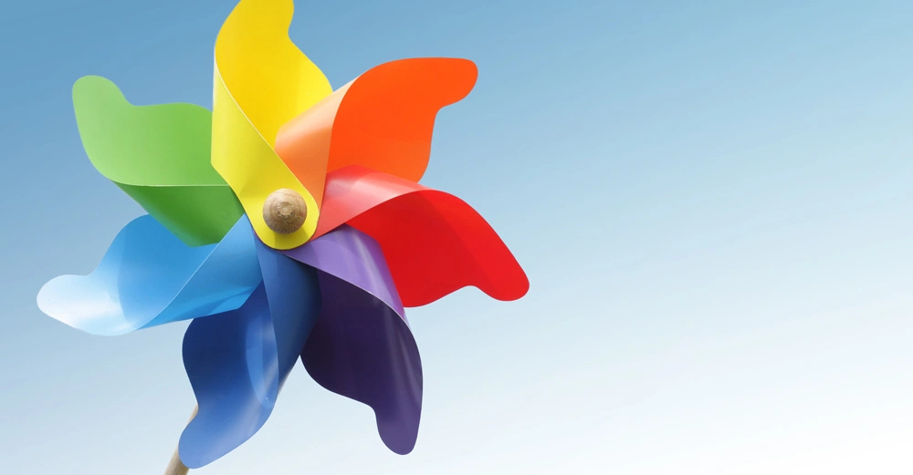 Bunter Windrad dreht sich gegen einen blauen Himmel.