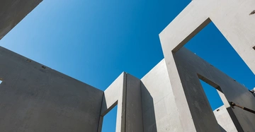 Betonwände ragen in den Himmel mit offenen Rahmen rechteckiger Fenster unter einem klaren blauen Himmel an einem sonnigen Tag Baustellenumgebung.