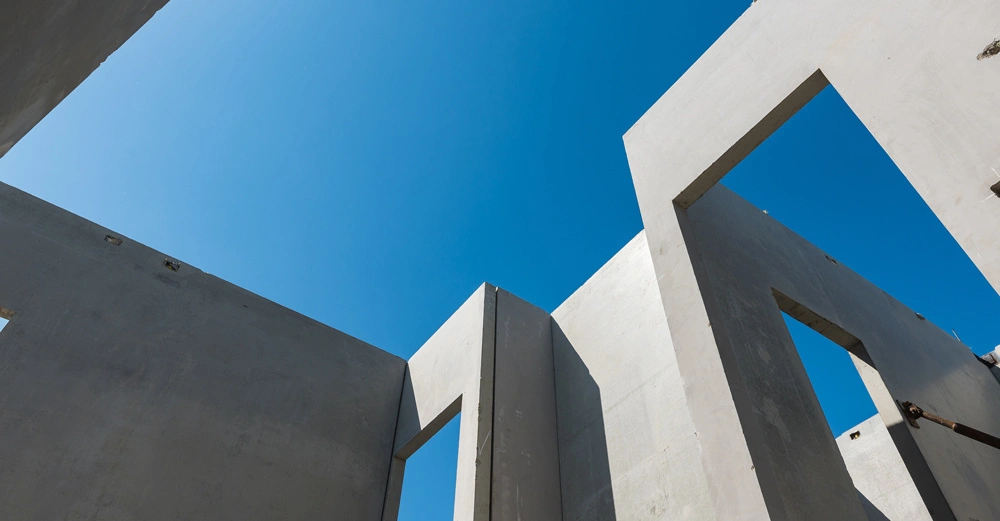 Betonwände ragen in den Himmel mit offenen Rahmen rechteckiger Fenster unter einem klaren blauen Himmel an einem sonnigen Tag Baustellenumgebung.
