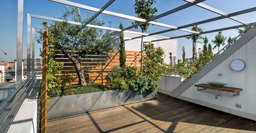 Urbane Dachterrasse mit niedriger Attika, Holzriemenboden und begrünter Wand. Gerüst für Überdachung mit Segel sichtbar. sonniger Tag mit blauem Himmel