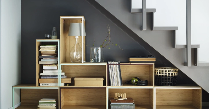 Galerie-Bild 6: Regaleinheiten unter die Treppe mit Büchern und Dekorationsgegenständen wie einer Glaslampe und Vasen Wohnzimmer Beige Teppichwand dunkelgrau Treppe weiß grau.