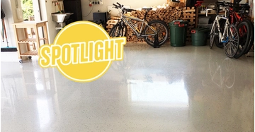 Blick in eine Garage mit Holz, Fahrrädern, Mülltonnen, Regalen. Boden glänzt hochwertig.