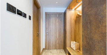 schmaler Flur mit viel Holz, eleganter Garderobe, indirekte Beleuchtung