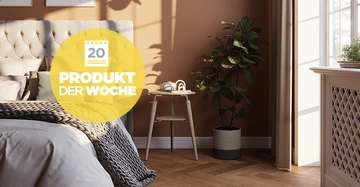 Lichtdurchflutetes Schlafzimmer mit gemütlichem Doppelbett, neben dem ein hölzernem Beistelltisch im Skandi-Stil steht.