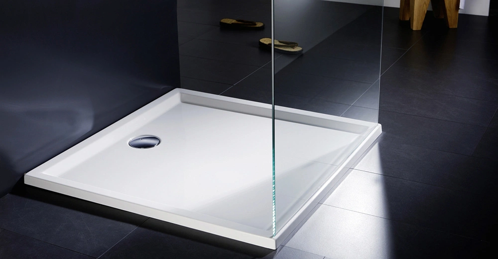 flache weiße Duschwanne in schwarzer Dusche von Repabad, Glasduschtüre halb offen. Moderner Anblick. 