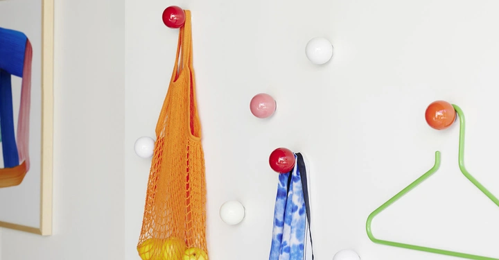 Galerie-Bild 5: Runde Wandhaken von Vitra in Weiß, Rot und Rosa in unregelmäßigen Abständen an einer weißen Wand montiert