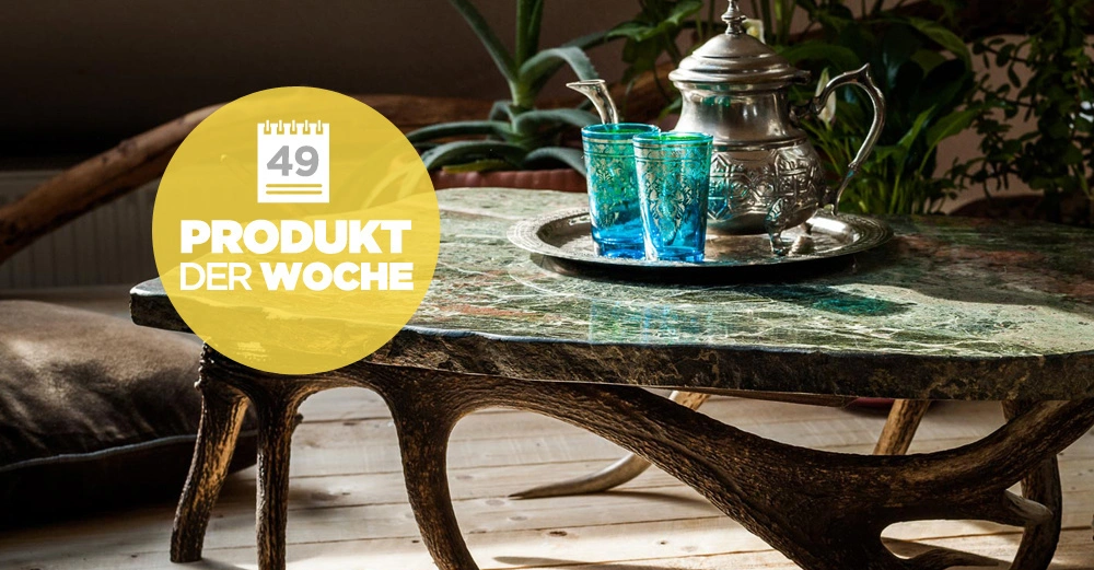 Teekanne und Gläser stehen auf einem Marmortisch im Wohnzimmer zusammen mit Topfpflanzen Text im gelben Kreis lautet 49 PRODUKT DER WOCHE