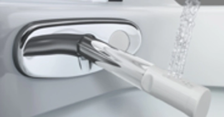 Ein Bidetaufsatz sprüht Wasser in einem Badezimmer auf einen weißen Porzellansitz.