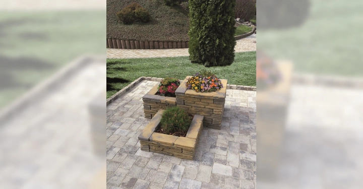 Galerie-Bild 3: Steinblumenbeete mit bunten Blumen befinden sich auf einer gepflasterten Terrasse im Garten. Grünflächen und Sträucher umgeben die Struktur.