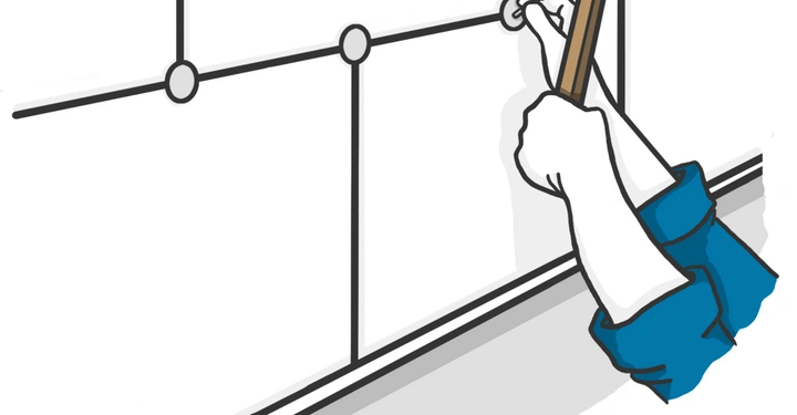 Eine Hand hält einen Hammer und schlägt einen Nagel in eine Wand die aus weißen Fliesen mit schwarzen Linien besteht.