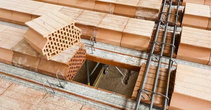 ZIegeldecke mit eingehängten Füllziegeln von oben, Stahlbewehrung und Träger zu sehen. zwei Ziegel noch nicht eingehängt