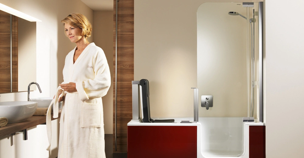 Eine Frau in einem weißen Bademantel steht vor dem Waschbecken in einem modernen Badezimmer mit einer integrierten Badewanne und Dusche vor einer holzverkleideten Wand. Text: keine.