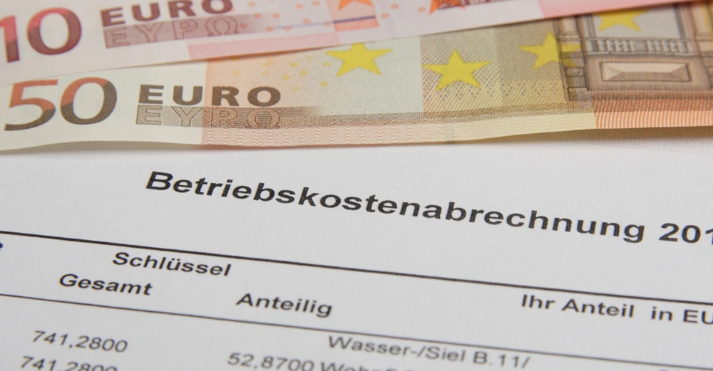 Bildausschnitt einer Betriebskostenabrechnung mit den anteiligen Kosten für Wasser. Ein 10 Euro und ein 50 Euro Schein liegen dahinter