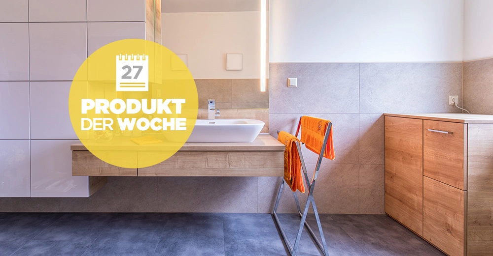 Ein hölzerner Waschtisch mit Waschbecken in einem modernen Badezimmer, Handtücher auf einem Handtuchhalter, daneben ein Holzschrank. Text: 27 PRODUKT DER WOCHE.