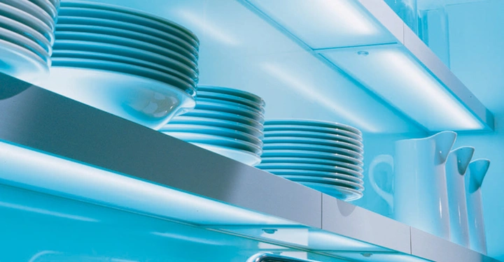 Galerie-Bild 4: Gestapelte weiße Teller und Schüsseln auf beleuchteten Regalen in einer modernen Küche blaue Beleuchtung und weiße Krüge im Hintergrund