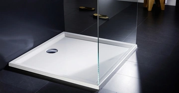 flache weiße Duschwanne in schwarzer Dusche von Repabad, Glasduschtüre halb offen. Moderner Anblick.