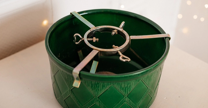 Grüner Christbaumständer in Topf-Optik mit Rautenmuster und innerer Metallhalterung mit Schrauben.
