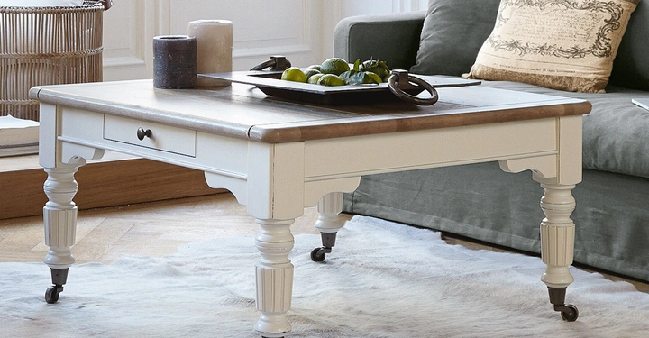 Galerie-Bild 3: Ein weißer Couchtisch mit Holzplatte steht auf einem Teppich vor einem grauen Sofa mit Kissen In der Mitte des Tisches befindet sich ein Tablett mit Obst und Dekorationsgegenständen.