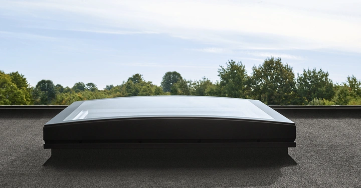 Dachfenster ist geschlossen montiert auf einem flachen Dach Bäume und Himmel im Hintergrund