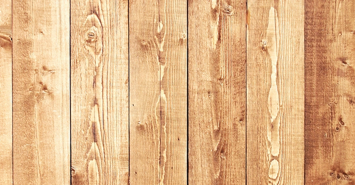 Holzbretter mit sichtbarer Maserung sind parallel zueinander angeordnet, bilden eine Oberfläche in einer Innen- oder Außenumgebung.