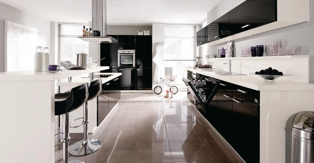 Moderne Küche mit schwarzen und weißen Möbeln Stehtische mit Barhockern Milchflaschen Tassen und Kochutensilien auf der Arbeitsfläche Geschirrspüler ist geöffnet Ein Licht durchfluteter Raum mit großen Fenstern und glänzendem Fliesenboden