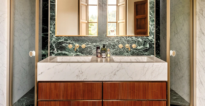 Modernisiertes Renaissance-Juwel in der Toskana: Weißer Carrara- und schwarzgrüner Verde delle Alpi-Marmor, außerdem Walnussholz. Gemeinsam mit den Dornbracht Vaia-Armaturen in Gold gebürstet (23,9kt) schaffen sie eine dezent luxuriöse Atmosphäre. Die ausgewogenen und elegant reduzierten Formen der von Sieger Design entworfenen Armaturen tragen ihren Teil dazu bei, Alt und Neu miteinander zu verbinden.
