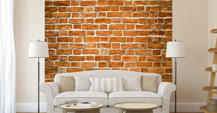 Zweisitziges Sofa steht vor einer gemauerten Backsteinwand mit zwei Stehlampen und einem Couchtisch im Wohnzimmer. Vorhänge und ein Bücherregal sind ebenfalls zu sehen.