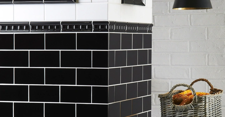 Galerie-Bild 4: Schwarzer Fliesenspiegel in einer Küche mit Körben und Brötchen vor einer weißen Backsteinmauer und einer schwarzen Hängeleuchte.
